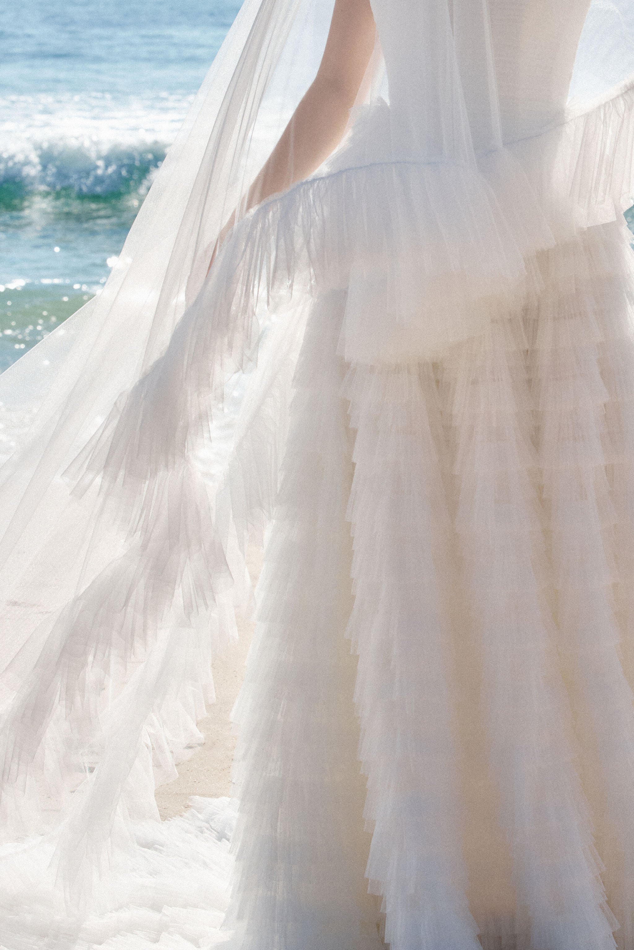 Detailaufnahme von einem extravaganten Brautkleid und einem Schleier aus weichen Tüll schichten
