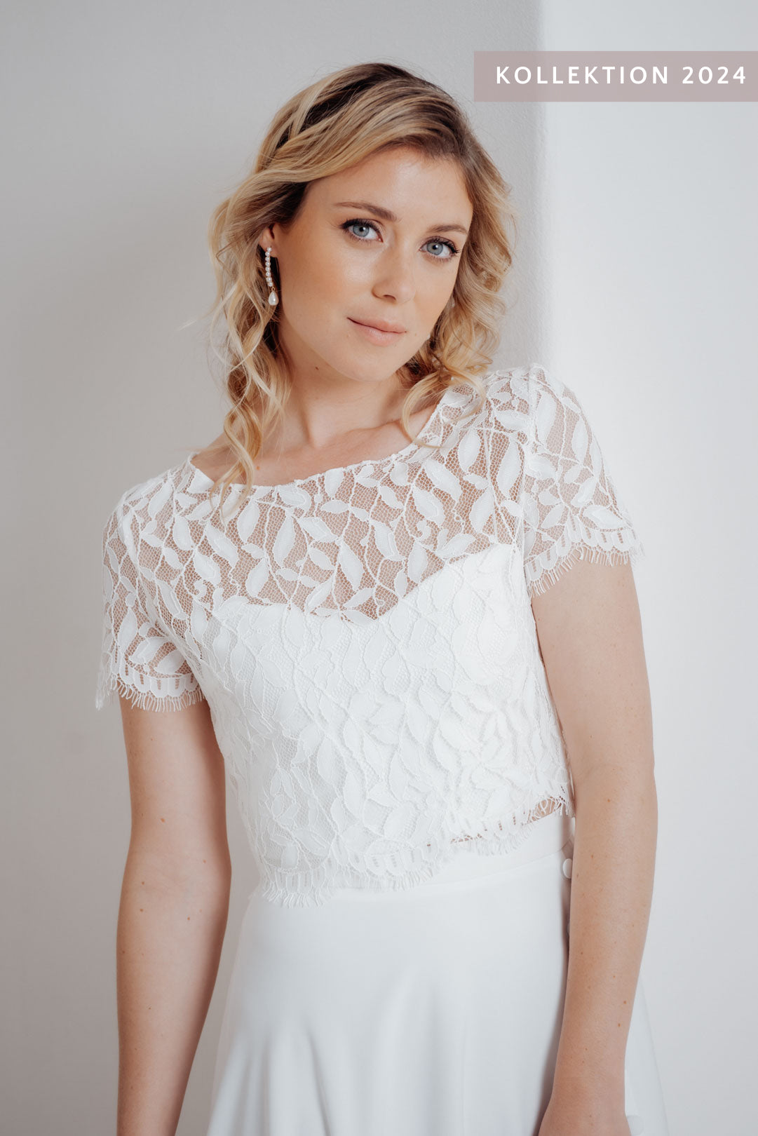 Braut trägt das Elva Braut Top – halbtransparentes Spitzenoberteil mit Blättermuster und ausgefransten Ärmeln.