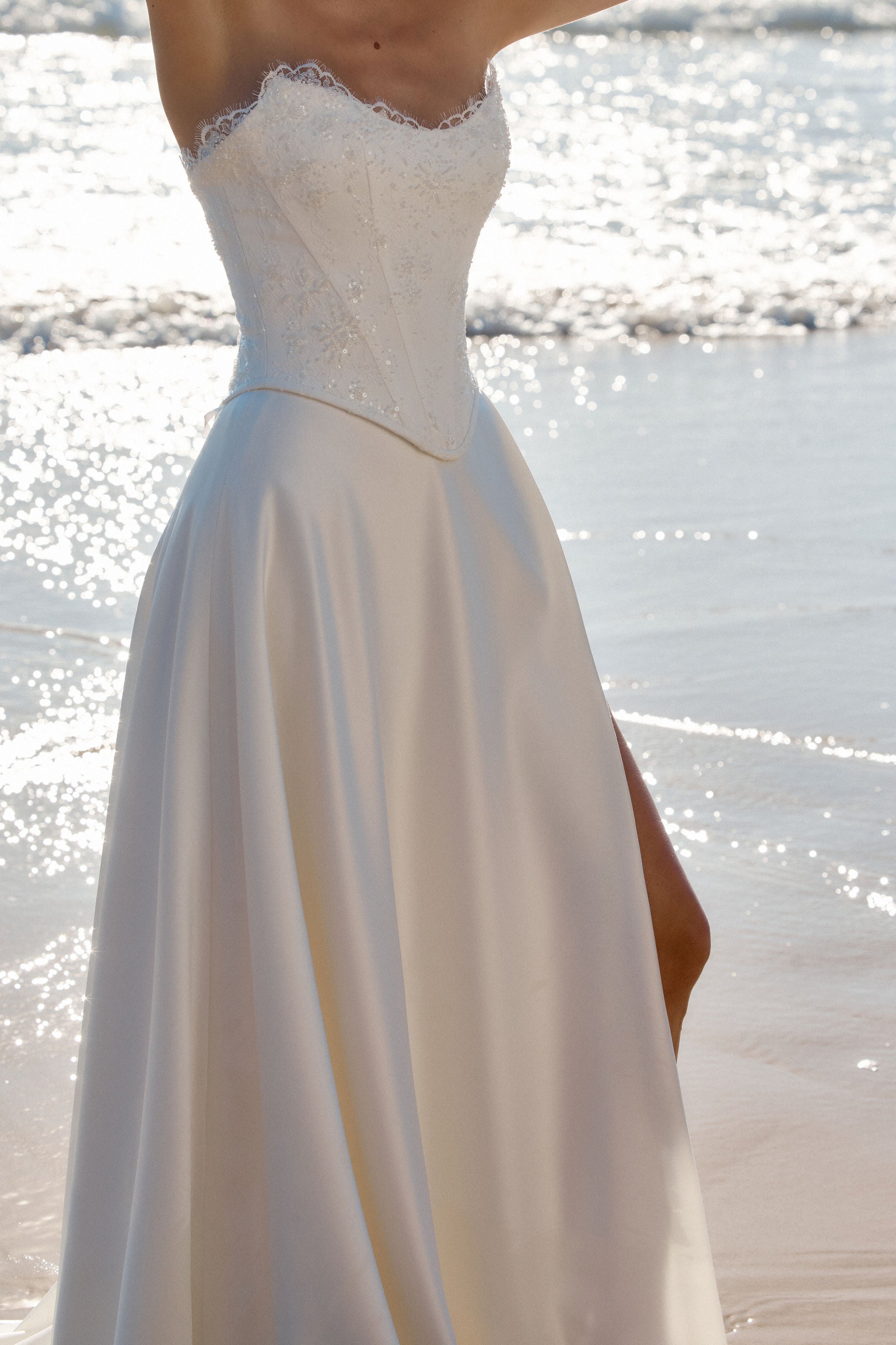 Modernes Brautkleid mit Struktur für eine stilvolle Präsenz. Die Korsage ist mit feiner Spitze verziert, fließender satin Rock rundet den gesamt Look ab.